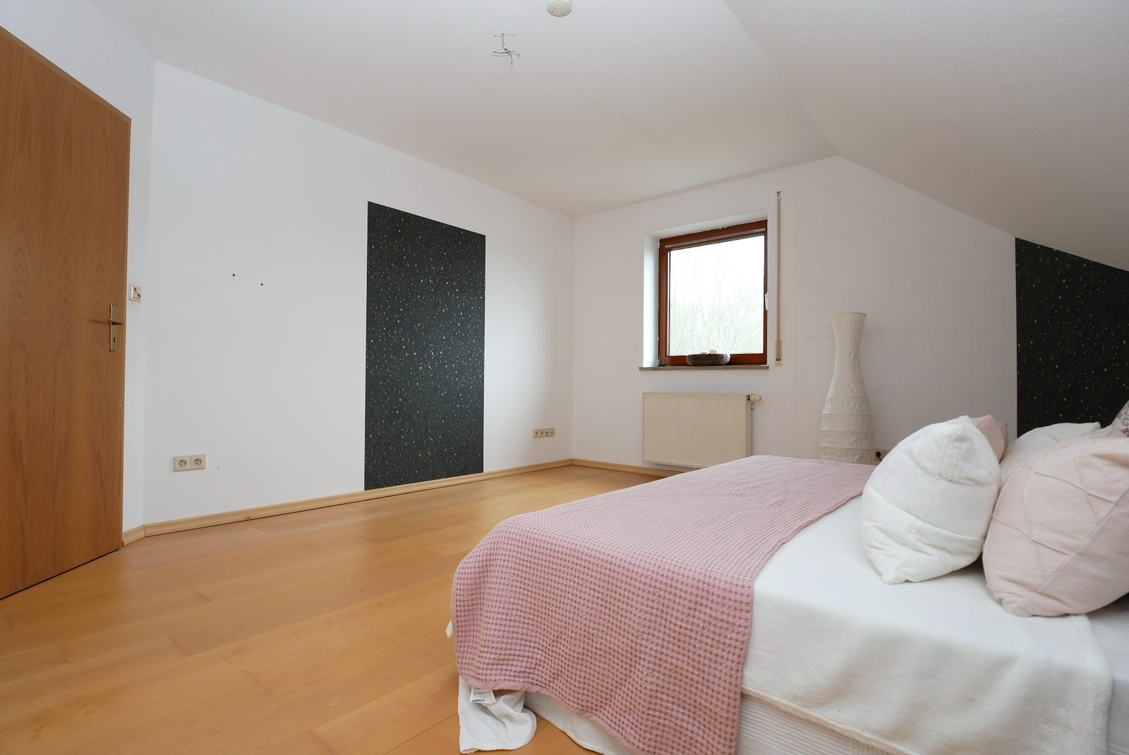 Schlafzimmer nach dem Home Staging: Bett mit Tagesdecke und Kissen, Vase am Fenster