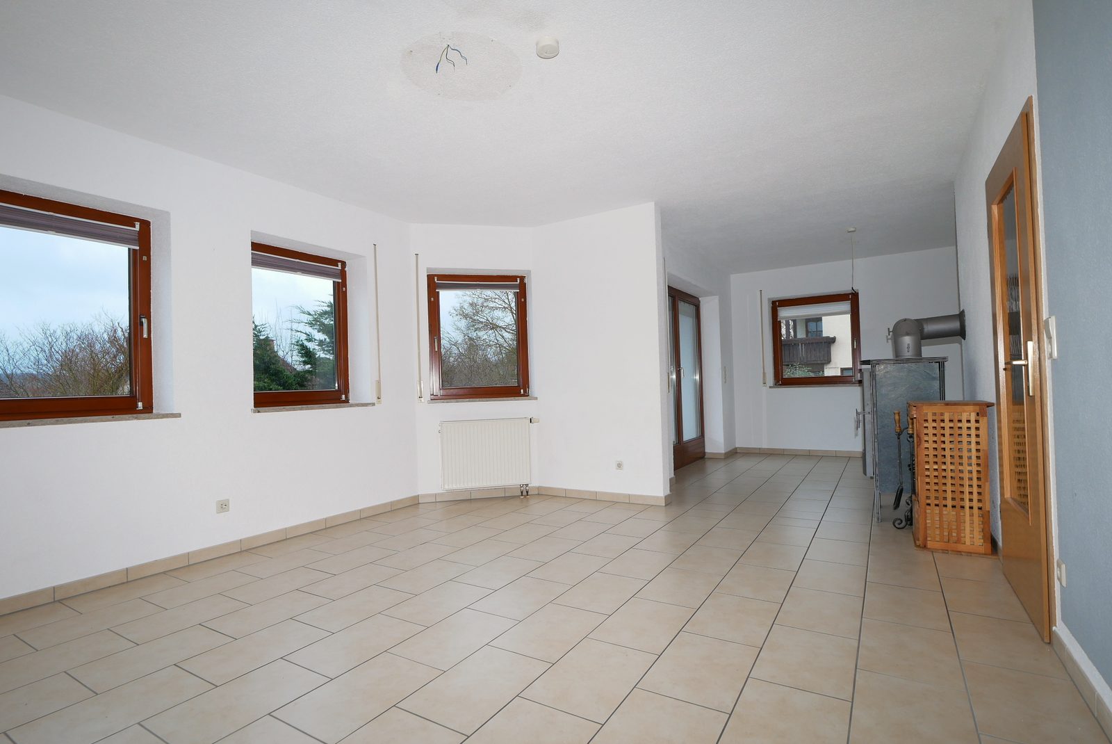 Wohnzimmer vor dem Home Staging: leerer Raum mit Fliesen und Kaminofen