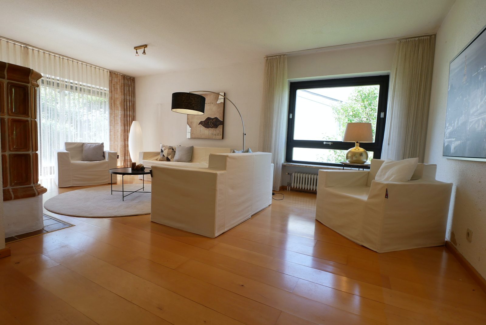 Wohnzimmer nach dem Home Staging: helle Sofas, runder Teppich, Bogenleuchte und Bild